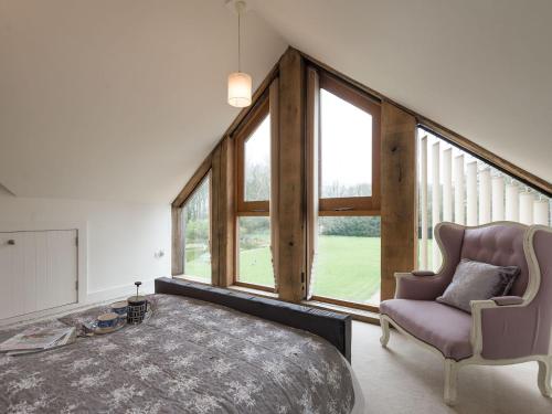 a bedroom with a bed and a chair and windows at Lily Pad Lodge in Donington on Bain
