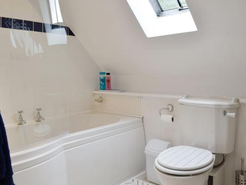 een witte badkamer met een toilet en een bad bij Beech Cottage in Rhewl