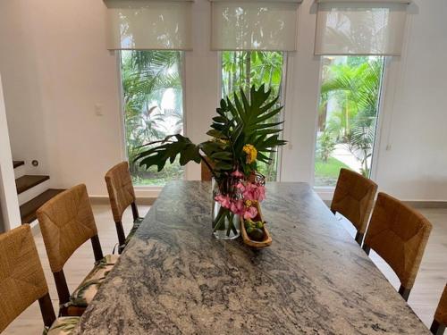a dining room table with a vase of flowers on it at Luxury Private Villas , Private Pool, Private garden, Jacuzzi, 24hours security in Tulum