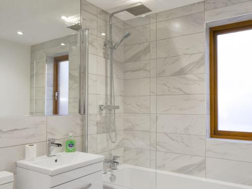 uma casa de banho branca com um chuveiro e um lavatório. em Waterside Lodge Sixteen - Uk13038 em Southowram