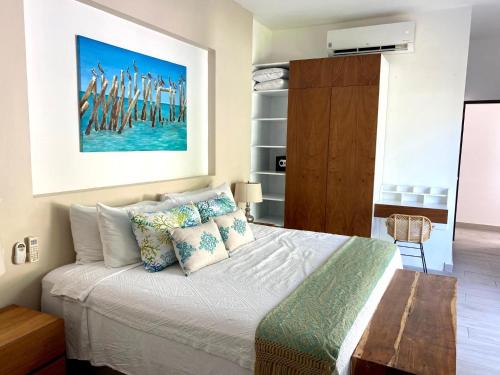 a bedroom with a bed with pillows and a painting at Luxury Private Villas , Private Pool, Private garden, Jacuzzi, 24hours security in Tulum
