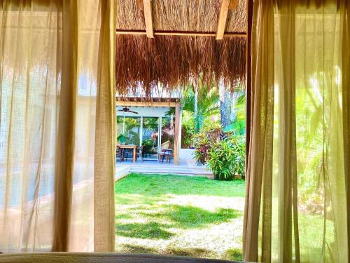 a view of a house from a window with curtains at Luxury Private Villas , Private Pool, Private garden, Jacuzzi, 24hours security in Tulum