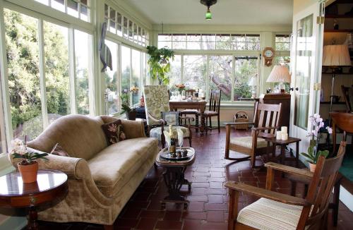 a living room with a couch and tables and windows at The Jabberwock Bed & Breakfast in Monterey