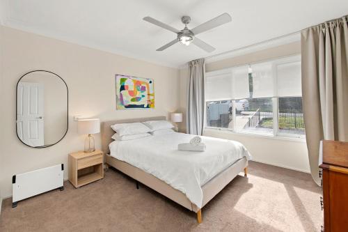 a bedroom with a bed and a mirror and a window at Summerside 43 Lentara Street in Fingal Bay