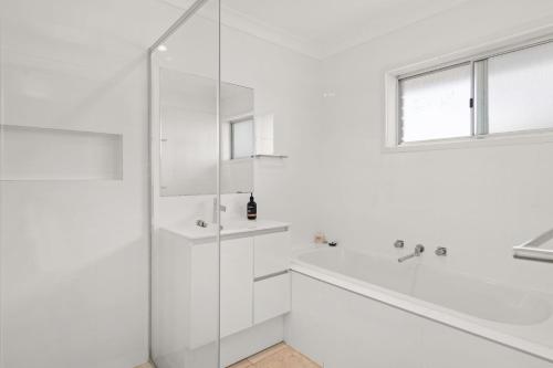 a white bathroom with a shower and a sink at Summerside 43 Lentara Street in Fingal Bay