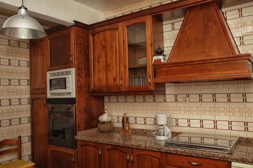 cocina con armarios de madera y microondas en Apartamentos Lalola en Cabezuela del Valle