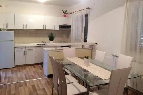 eine Küche mit einem Glastisch und weißen Schränken in der Unterkunft Apartment Zrnovska Banja 3154a in Korčula