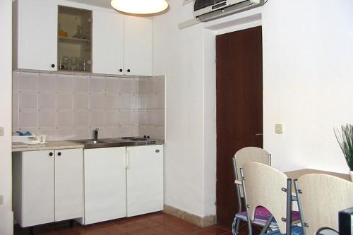 a kitchen with white cabinets and a table and chairs at Apartments by the sea Zrnovska Banja, Korcula - 3154 in Korčula