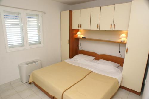 a bedroom with a bed with white cabinets and a window at Rooms by the sea Zuljana, Peljesac - 3163 in Žuljana