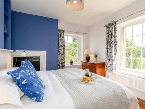 a blue bedroom with a bed with a tray of teddy bears on it at Colveston Manor in Cranwich
