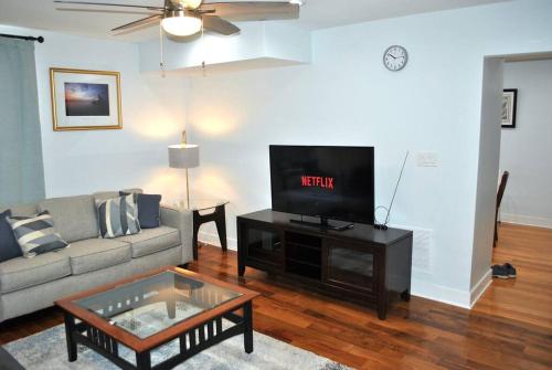 a living room with a couch and a flat screen tv at Stylish 4-Bedroom Full House. Plenty of Parking! in Catonsville