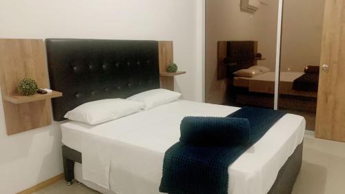 een slaapkamer met een wit bed met een zwart hoofdeinde bij Aloja-T en Apartamento amoblado en Condominio de San Jeronimo in San Jerónimo