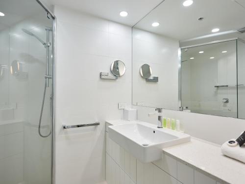 a white bathroom with a sink and a shower at Maldives Resort Main Beach, Gold Coast in Gold Coast