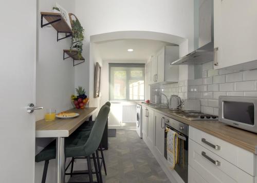 a kitchen with white cabinets and a table with chairs at Birmingham Contractor House sleeps 8 Private Garden near M6 Motorway Business Wi-FI in Birmingham
