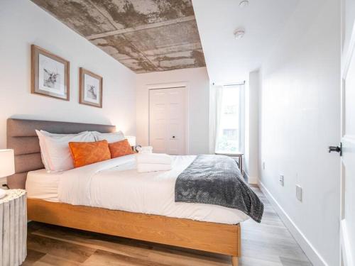 um quarto com uma cama grande e almofadas laranja em Le Rustique, Chic en Ville, BBQ/ Piscine em Cidade de Quebec
