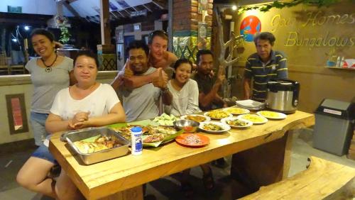 a group of people sitting at a table with food at Gede Homestay in Lovina