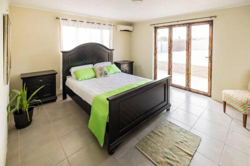 een slaapkamer met een groot bed en een groene deken bij Enjoyment Villa Cataleya in Oranjestad