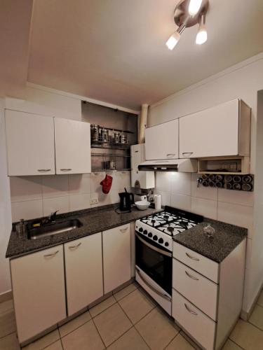 a kitchen with white cabinets and a stove top oven at Paraná Confort in Paraná