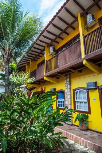 a yellow house with a balcony and a palm tree at Pousada Konquista in Paraty