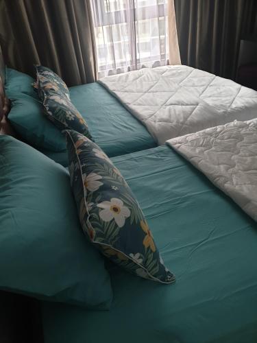 ein Bett mit grüner Bettwäsche und Kissen darauf in der Unterkunft ICity Homestay Konvokesyen Dan Percutian Shah Alam 1R 1Q 1S 1Sofabed in Shah Alam