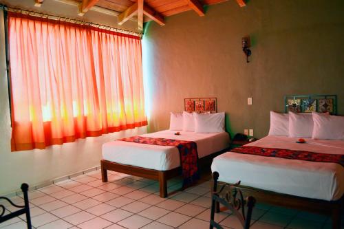 a hotel room with two beds and a window at Hotel Aldama in Colima