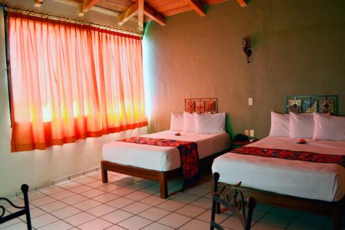 um quarto de hotel com duas camas e uma janela em Hotel Aldama em Colima