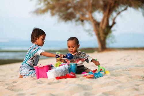 two young children playing in the sand on the beach at The Seraya Resort Komodo in Labuan Bajo