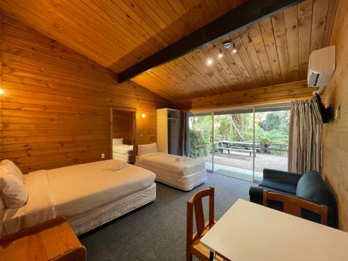 Lakes Lodge Okataina في روتوروا: غرفة فندقية بسريرين وطاولة وكراسي