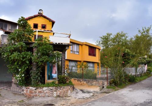 una casa amarilla con una valla delante de ella en Apartamento Campestre la Casa de Leo en Paipa