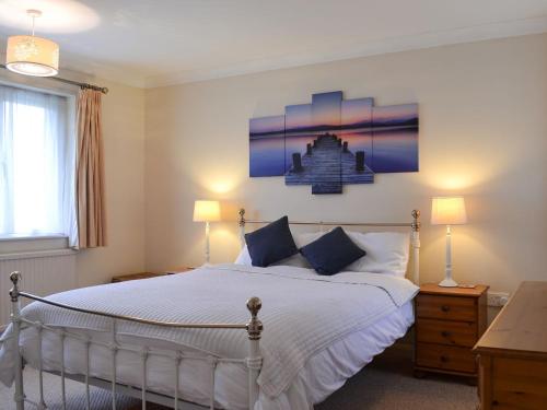 1 dormitorio con 1 cama blanca grande y 2 lámparas en The Cottage At Boscobel en Brockenhurst