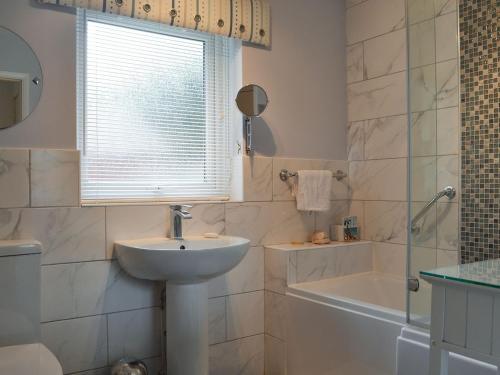 y baño con lavabo, ducha, bañera y lavamanos. en The Cottage At Boscobel en Brockenhurst