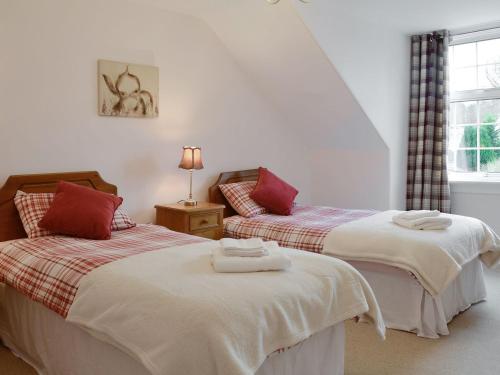 two beds sitting next to each other in a bedroom at Burnbrae Cottage in Bridgend of Lintrathen