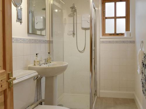 y baño blanco con lavabo y ducha. en Burnbrae Cottage en Bridgend of Lintrathen