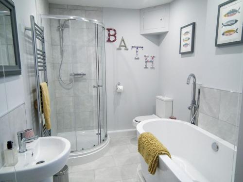 a bathroom with a shower and a tub and a sink at Little Vines in Strensham