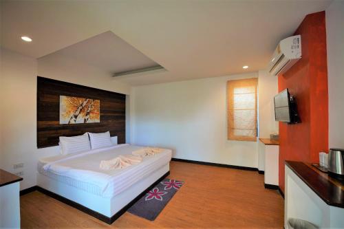 1 dormitorio con 1 cama blanca y TV en Annowa Resort - Chanthaburi, en Chanthaburi