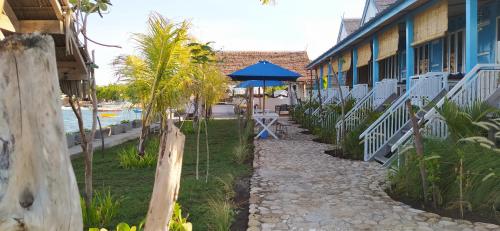 a walkway next to a building with a blue umbrella at Moyo Island Resort in Moyo Island