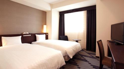 a hotel room with two beds and a flat screen tv at JR-East Hotel Mets Yokohama Tsurumi in Yokohama