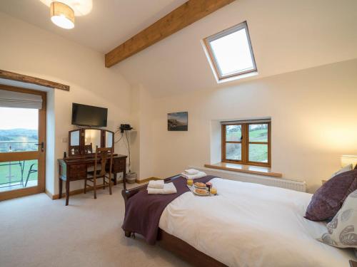 a bedroom with a bed and a desk and windows at Ysgubor in Efenechtyd