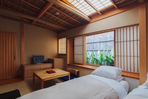 a bedroom with a bed and a table and a window at Ryokan Motonago in Kyoto