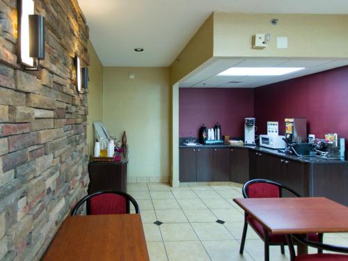 a restaurant with tables and chairs and a counter at Travelodge by Wyndham Romulus Detroit Airport in Romulus