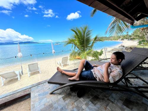 a young boy laying on a chair on the beach at The Shore Samui in Bang Rak Beach