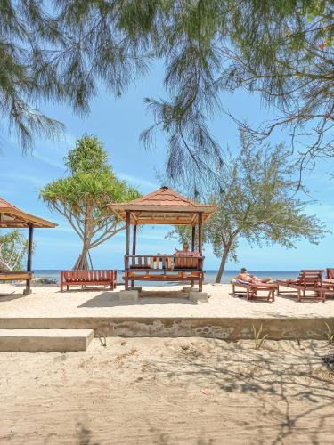 a group of benches sitting on the beach at Nusa Indah Bungalows in Gili Islands