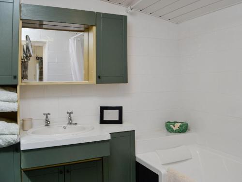 y baño con lavabo y espejo. en Belstane Cottage en Straiton
