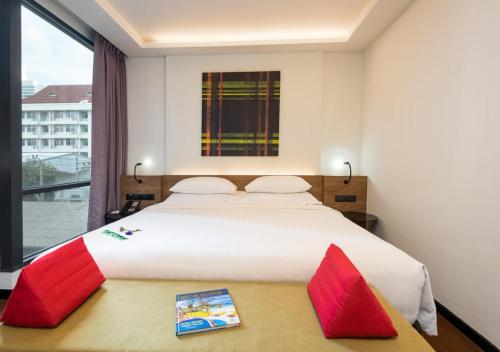 a bedroom with a large white bed with red pillows at Maitria Mode Sukhumvit 15 Bangkok - A Chatrium Collection in Bangkok