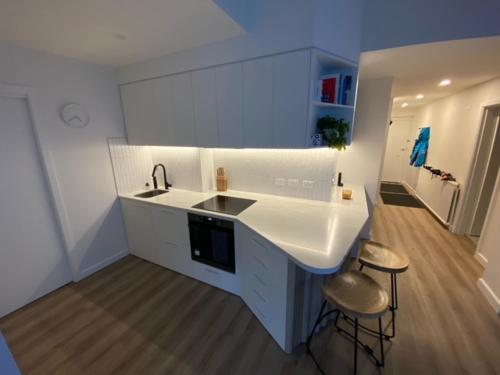a white kitchen with a sink and two stools at Arlberg 314 in Mount Buller