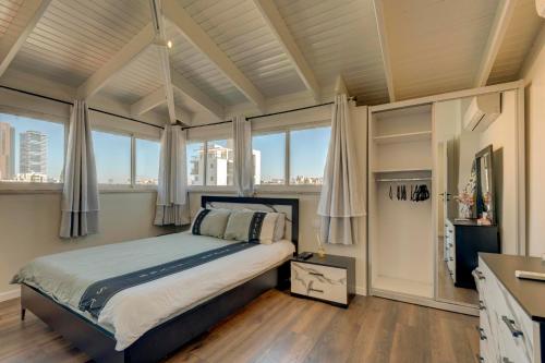 1 dormitorio con 1 cama y ventanas grandes en LUXURY PENTHOUSE GREAT LOCATION WITH PARKING Tlv, en Ramat Gan