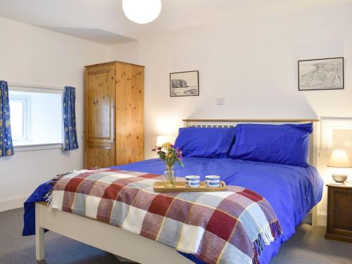 a bedroom with a blue bed with a tray with flowers on it at 3 Covesea Village in Duffus