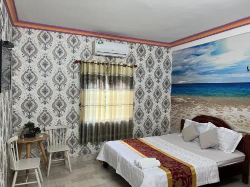 a bedroom with a bed and a painting of the ocean at Nhà Nghỉ Hồng Trang - Thủ Dầu Một in Xóm Mới (1)