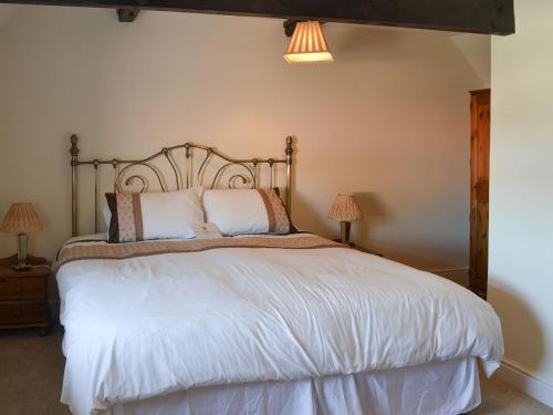 a bedroom with a large white bed with two lamps at Granary Cottage - Uk10994 in Eshott
