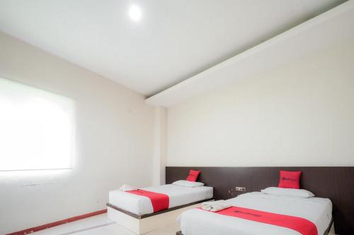 two beds in a white room with a window at RedDoorz near Pantai Pede in Labuan Bajo